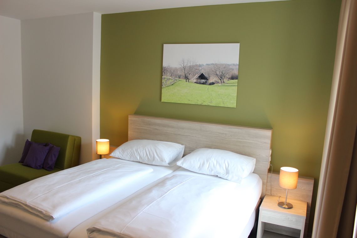 Doppelbett, Ansicht von vorne, Bild von Haus an grüner Wand